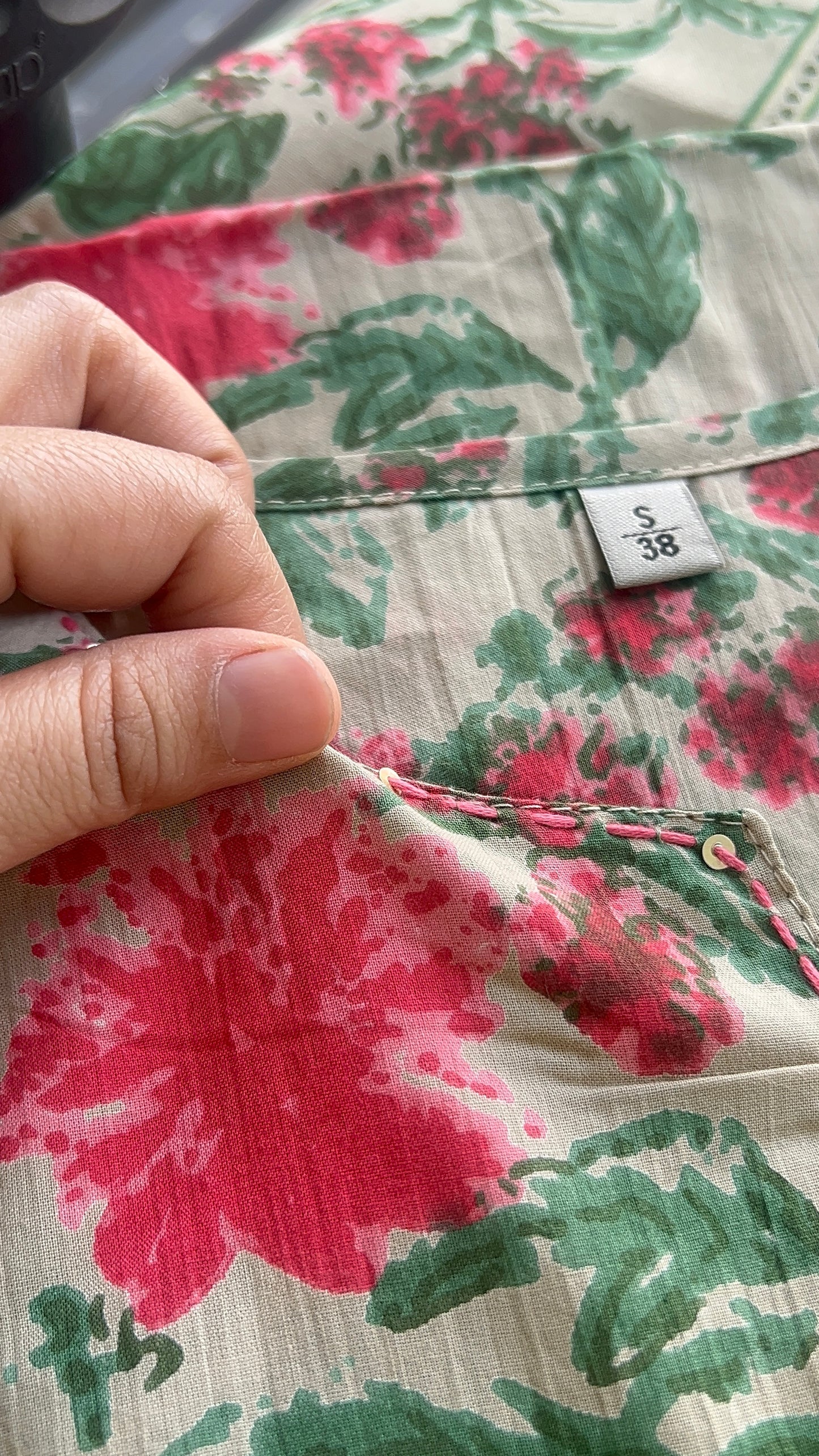 Floral-patterned fabric with a hand and size label visible